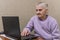 An elderly woman communicates on a laptop via video calling