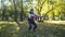 Elderly woman does physical exercises with nordic sticks in her hands in meadow grass in park sunny weather. Senior