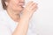 Elderly woman drinks water from a glass on a white background, concept of loss of body fluid in the elderly, dehydration