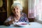 An elderly woman eating soup sitting at a table.