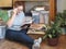 An elderly woman is engaged in her favorite pastime, reading books in a room with wooden shelves. Storage space for household