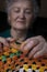 An elderly woman is engaged in needlework. Grandmother crochets napkin.