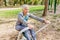 Elderly Woman Exercising At Outdoor Fitness Park With Rowing Machine