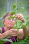 Elderly woman farmer ties up cucumber plants