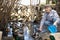 Elderly woman feeds domestic ducks on shore of man-made pond in the backyard of farm