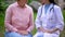 Elderly woman and female doctor talking sitting hospital garden, consultation