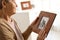 Elderly woman with framed family portrait