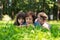 Elderly woman, girl and boy are lying on the lawn and reading a book against green nature background.Grandmother and grandchildren