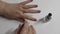 An elderly woman gives herself a manicure with a brown varnish with sequins. White background. Close-up on the fingers