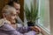 An elderly woman, a grandmother looks out the window, a granddaughter approaches her and hugs, a happy family