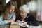 Elderly woman granny is reading a book to her beloved granddaughter. Family.