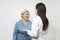 An elderly woman has a cute conversation with a young doctor. They are happy to see each other and smile.