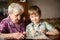 Elderly woman with her little grandson looking album. Family.