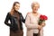 Elderly woman holding a bunch of red roses and posing with a young woman