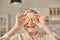 An elderly woman holds bitcoin coins in her hands near her eyes. Seniors retirement happy life concept