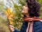 Elderly woman holds an oak branch with yellow leaves and looks up, admiring nature