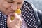 An elderly woman holds a small duckling in her hands. Love for animals