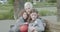 Elderly woman hugs and tickles two young children as they sit on a park bench, the young boy is holding a basketball