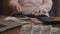 An elderly woman keeps a record of savings. Close-up hands of an elderly woman pensioner believe dollar bills.