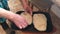 An elderly woman kneads bread dough and puts it on a baking sheet. You can see her working hands.