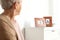 Elderly woman looking at framed  portraits indoors