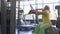 Elderly woman makes pull up exercise on training apparatus in the gym