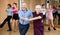 Elderly woman and man practicing jitterbug moves in dance studio