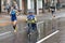 Elderly woman moving on a wheel-chair next to ordinary athletes on a rainy city street during 10 km section of ATB Dnipro Marathon