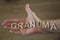 An elderly woman one hand open with wooden letters forming the word Grandma