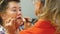 Elderly woman is painting her friend`s lips for the party.