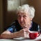 An elderly woman pensioner has breakfast sitting at kitchen