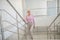 Elderly woman in a pink shirt slowly going upstairs
