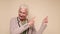 An elderly woman points her finger to attract attention on a beige background