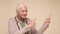 An elderly woman points her finger to attract attention on a beige background