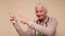 An elderly woman points her finger to attract attention on a beige background