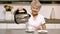 Elderly woman pouring boiling water from kettle into cup in kitchen