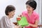 Elderly woman receiving a gift from daughter