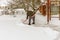An elderly woman removes snow from the road near her home