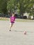 An elderly woman runs across the Playground with a soccer ball