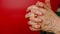 Elderly woman's hands on red background. Unrecognizable mature woman showing gesture of intertwined fingers.