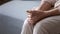 Elderly woman seated indoors folded palms on lap feeling loneliness