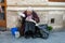Elderly woman selling flowers and read newspaper on city street