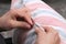 elderly woman while sewing with needle and thread the pillow