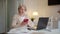 An elderly woman sits at a table and learns to use the phone on her own