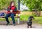Elderly woman sitting on bench and holding dachshund on leash