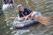 An elderly woman is smiling as she is rowing her truck tire with a broom in a flooded street of Bangkok, Thailand, on 31 October 2