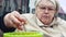 An elderly woman sorts out onions for planting in a basin close-up.