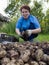 An elderly woman sorts a potato crop