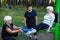 Elderly woman on a sports simulator in the Park, two adult women help her to do exercises. Sport.