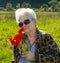 Elderly woman in sunglasses with bunch of poppies